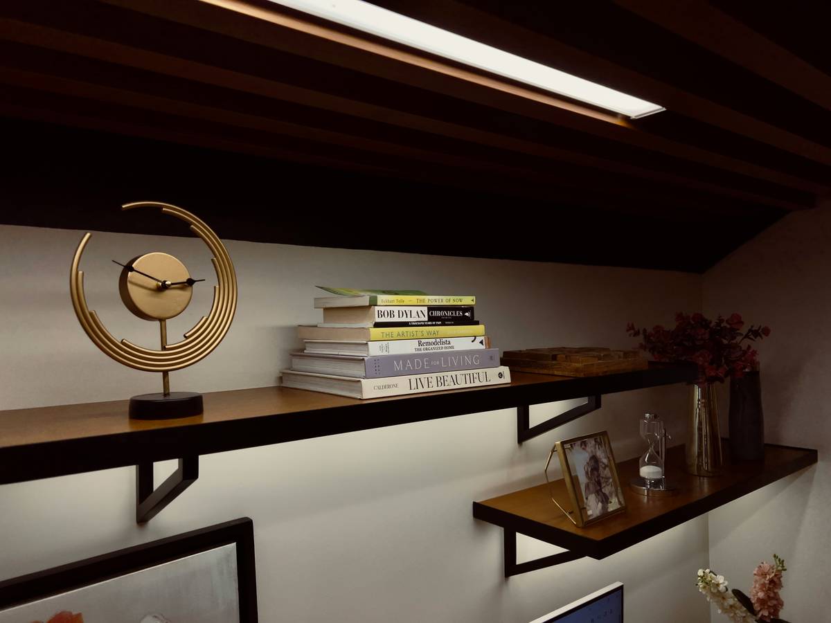 Vintage brass table clocks for living room decor arranged on a walnut console with books and a small plant