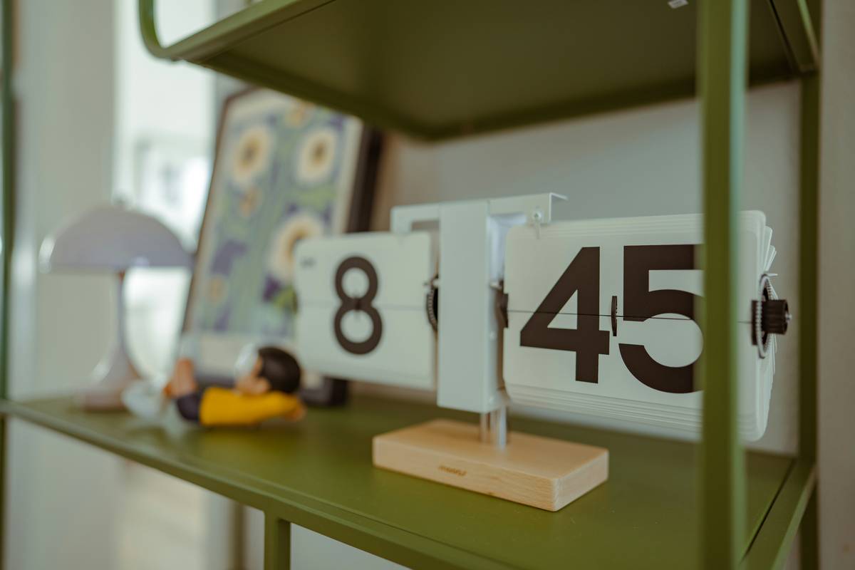 Elegant table top clocks for living room displayed on a wooden console table beside books and a small plant